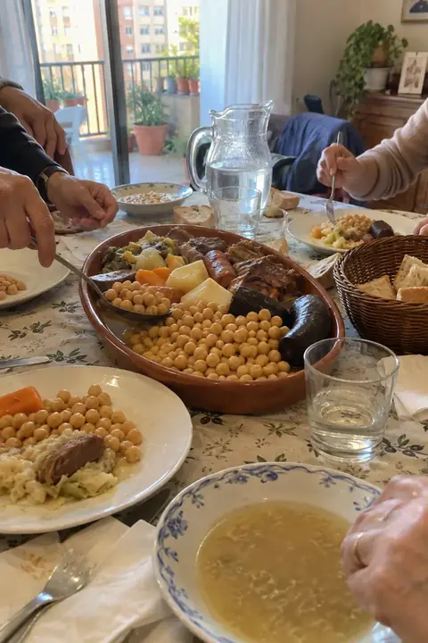 Mesa de domingo con una fuente de cocido, pan y platos